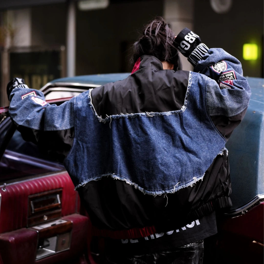 Sanhoostudio denim jacket featuring black patch applique embroidery, distressed surface detailing, and a relaxed oversized silhouette with added seasonal warmth. Designed for statement streetwear layering with rugged texture, handcrafted character, and versatile urban styling.