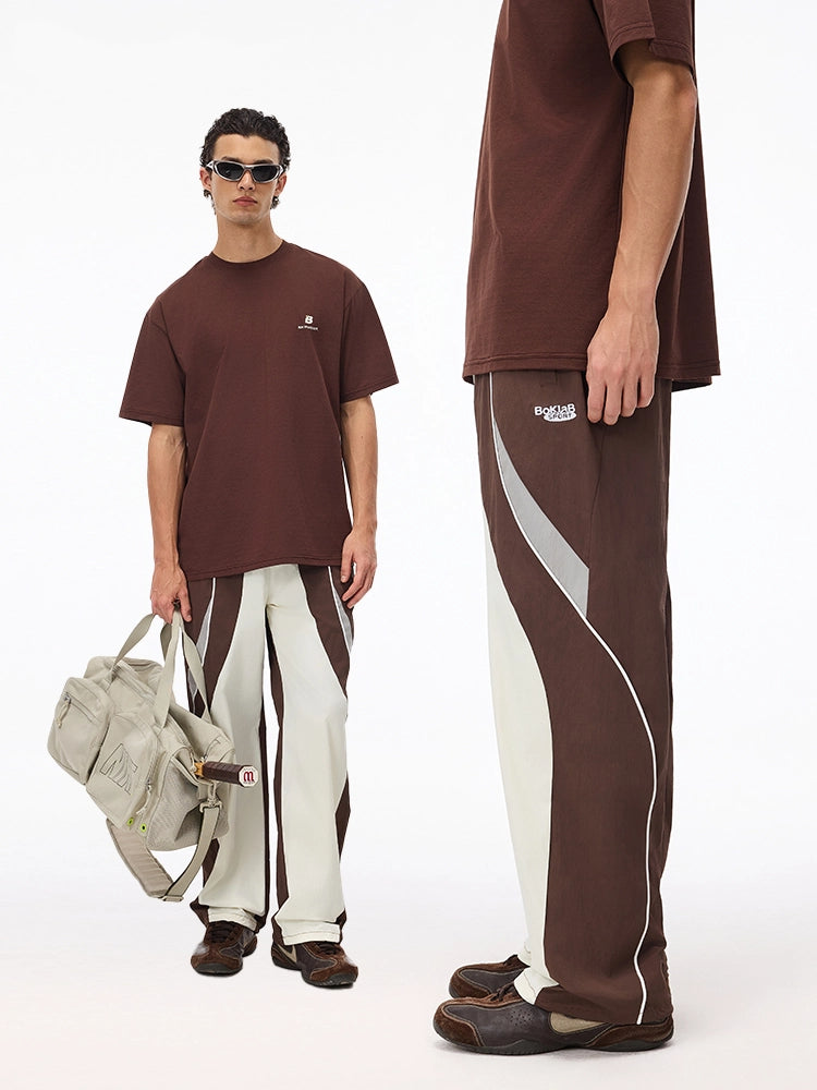 These vintage-inspired lightweight sport pants from Sanhoostudio feature a water-resistant finish and relaxed fit. Perfect for casual outings or streetwear looks with a retro athletic twist.