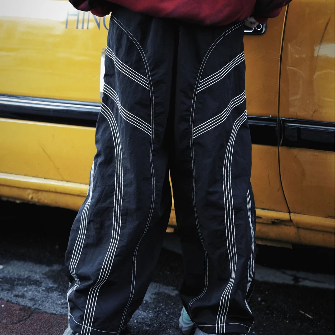 Straight-leg hip-hop pants featuring embroidered contrast stitching, deconstructed patchwork, and a dry-fit breathable build.