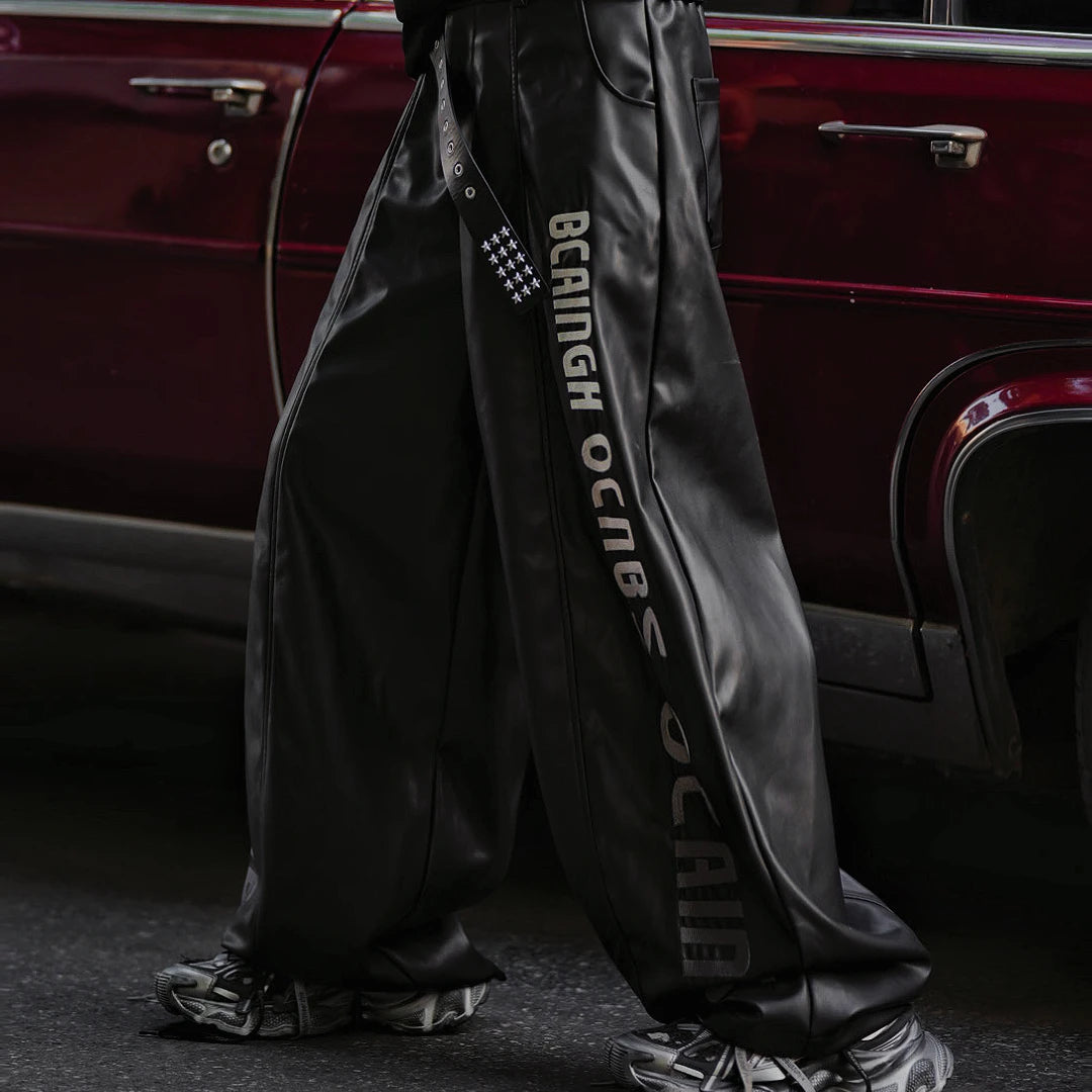 Sanhoostudio washed leather pants featuring gradient letter embroidery, distressed finish, and graffiti patchwork detailing. Heavyweight unisex streetwear pants designed for bold winter styling.