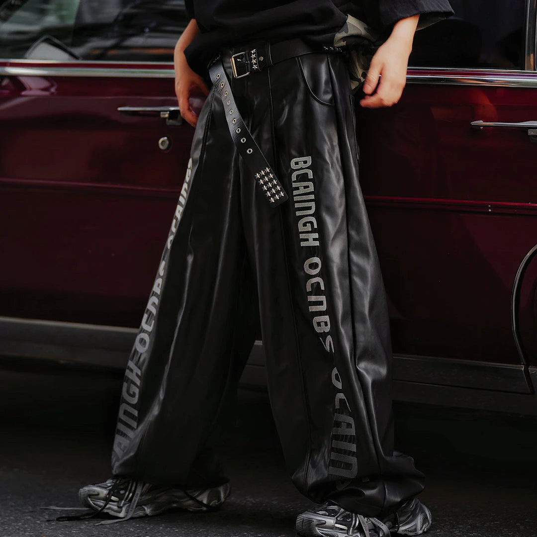 Sanhoostudio washed leather pants featuring gradient letter embroidery, distressed finish, and graffiti patchwork detailing. Heavyweight unisex streetwear pants designed for bold winter styling.