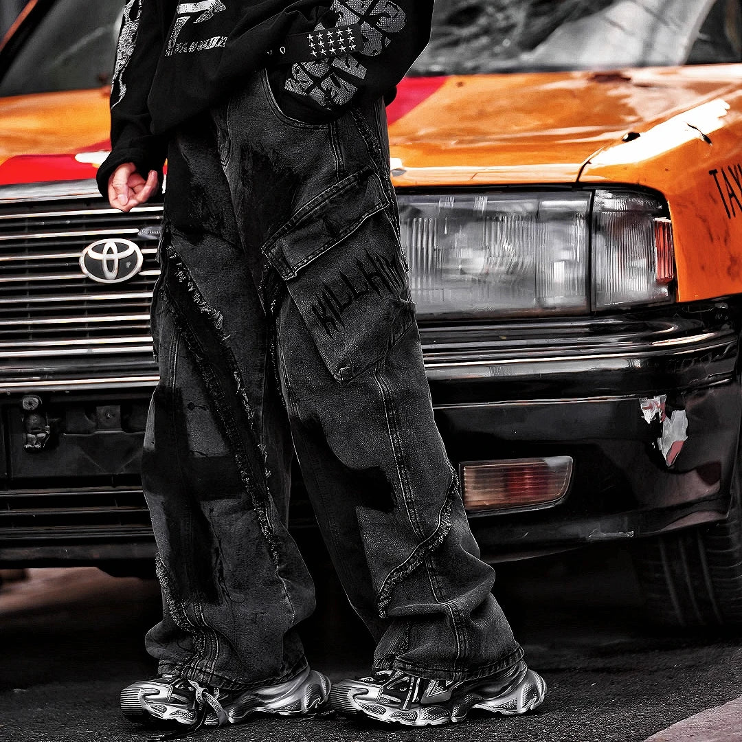 Sanhoostudio heavyweight denim featuring embroidery, graffiti artwork, and washed distressed finish. Designed with patchwork construction for bold unisex streetwear styling.