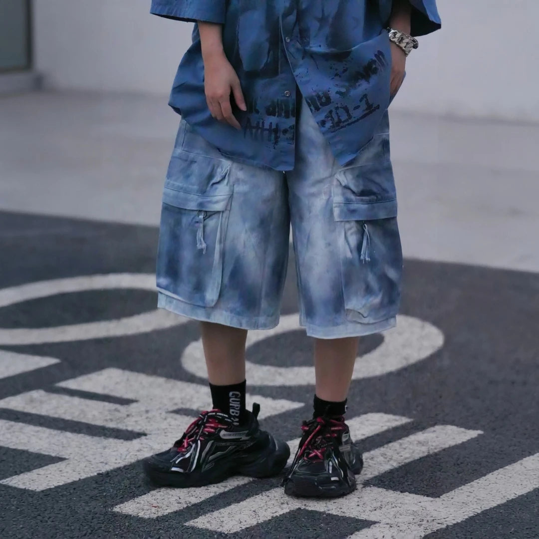 Sanhoostudio cargo shorts featuring tie dye finish, multi-pocket design, and relaxed wide leg fit. Built for summer streetwear styling with breathable comfort, lightweight feel, and functional everyday wear.