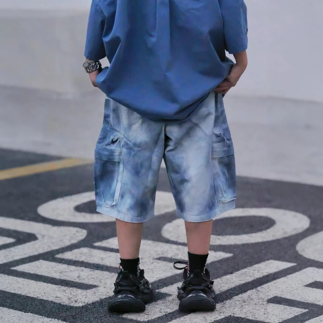 Sanhoostudio cargo shorts featuring tie dye finish, multi-pocket design, and relaxed wide leg fit. Built for summer streetwear styling with breathable comfort, lightweight feel, and functional everyday wear.
