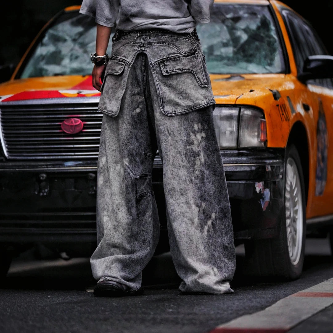 Sanhoostudio denim pants featuring layered patchwork construction, distressed wash finish, and detachable styling elements. Designed for bold streetwear outfits with relaxed comfort and unique visual structure.