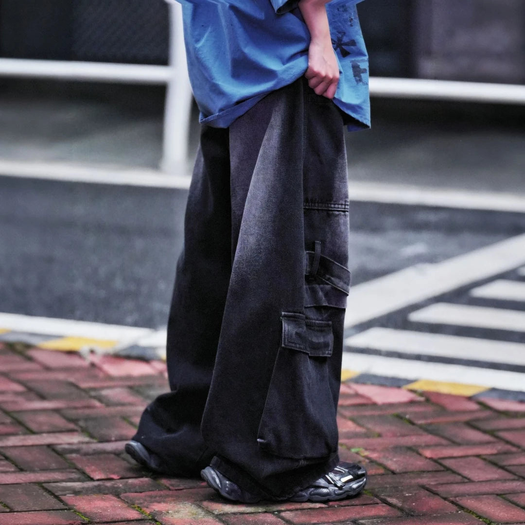 Sanhoostudio denim pants featuring colorblock patchwork construction, cargo-inspired details, distressed wash finish, and a wide leg scythe-cut silhouette. Designed for bold streetwear styling with comfort and versatility.