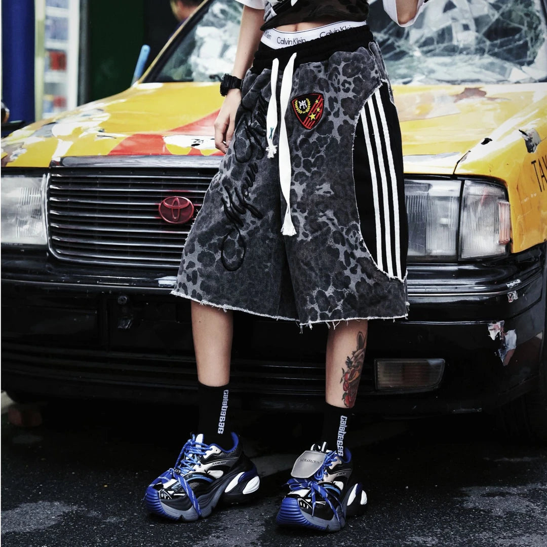 Sanhoostudio shorts featuring leopard print detailing, embroidered accents, and a relaxed scythe-inspired silhouette. Designed for summer streetwear styling with comfort, mobility, and bold visual impact.