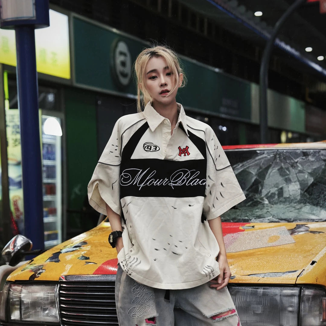 Sanhoostudio polo shirt featuring colorblock stripe detailing, letter-inspired accents, and a relaxed oversized fit. Designed for versatile summer outfits that blend casual comfort with modern streetwear aesthetics.