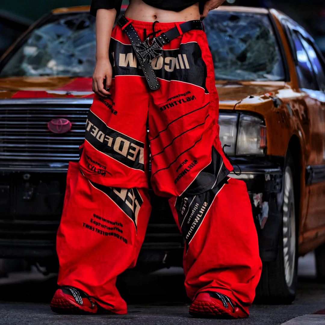 Sanhoostudio wide leg pants featuring detachable styling elements, racing-inspired panel construction, and a relaxed fit. Designed for modern streetwear outfits with comfort, versatility, and bold visual appeal.