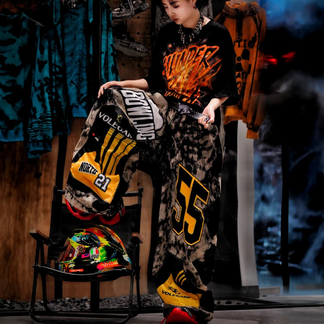 Sanhoostudio denim pants featuring patchwork applique details, distressed wash treatment, and a wide leg scythe-cut silhouette. Designed for contemporary streetwear styling with relaxed comfort and standout visual structure.