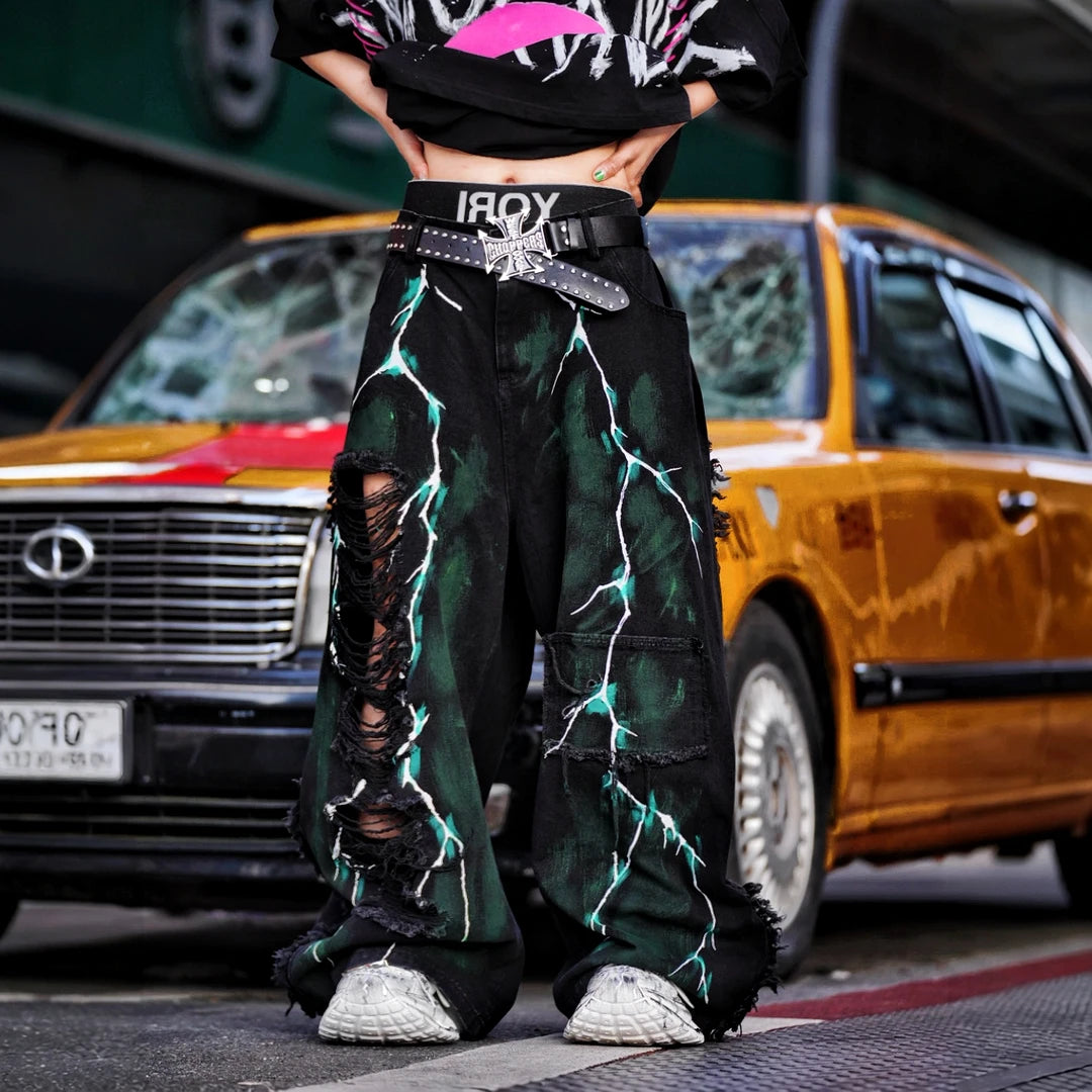 Sanhoostudio denim pants featuring graffiti artwork, distressed ripped detailing, and irregular patchwork construction. Designed for standout streetwear styling with a relaxed fit and bold visual identity.