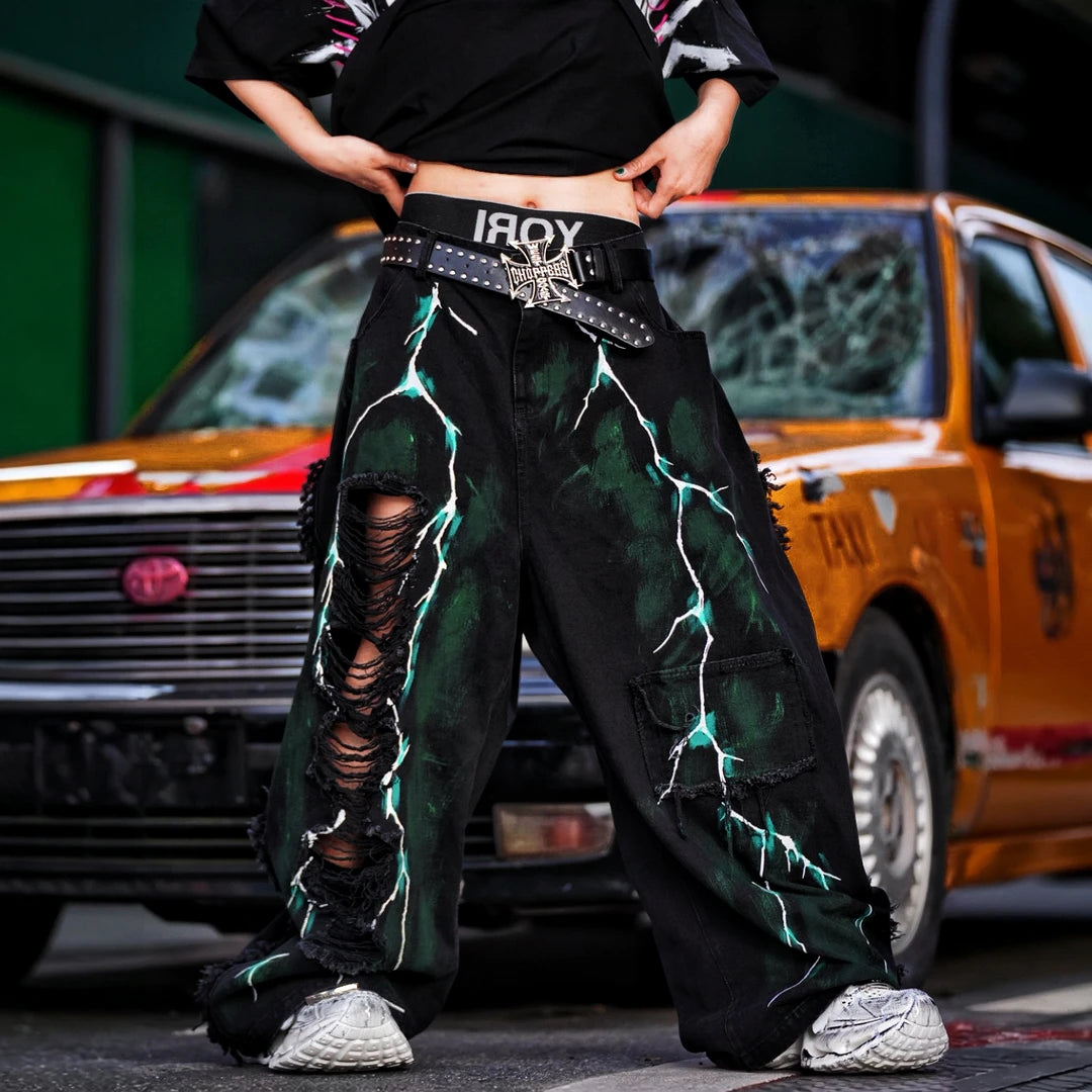 Sanhoostudio denim pants featuring graffiti artwork, distressed ripped detailing, and irregular patchwork construction. Designed for standout streetwear styling with a relaxed fit and bold visual identity.