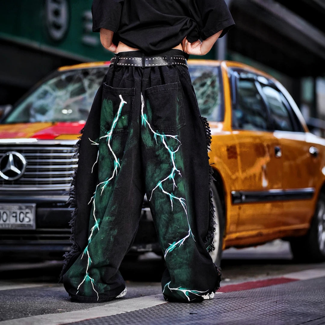 Sanhoostudio denim pants featuring graffiti artwork, distressed ripped detailing, and irregular patchwork construction. Designed for standout streetwear styling with a relaxed fit and bold visual identity.