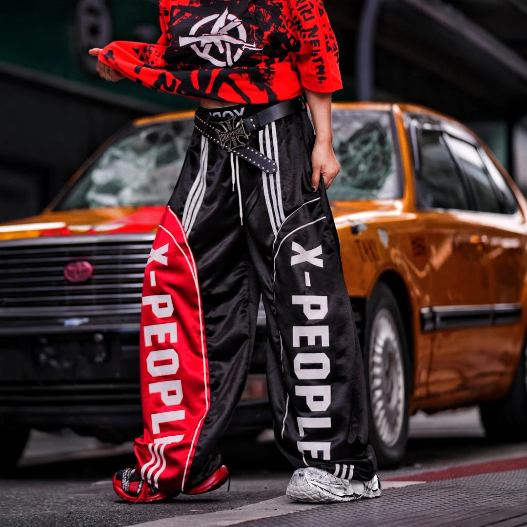 Sanhoostudio wide leg pants featuring lightweight glossy fabric construction and a scythe-cut silhouette with a relaxed fit. Designed for breathable summer styling with comfort, movement, and contemporary streetwear appeal.