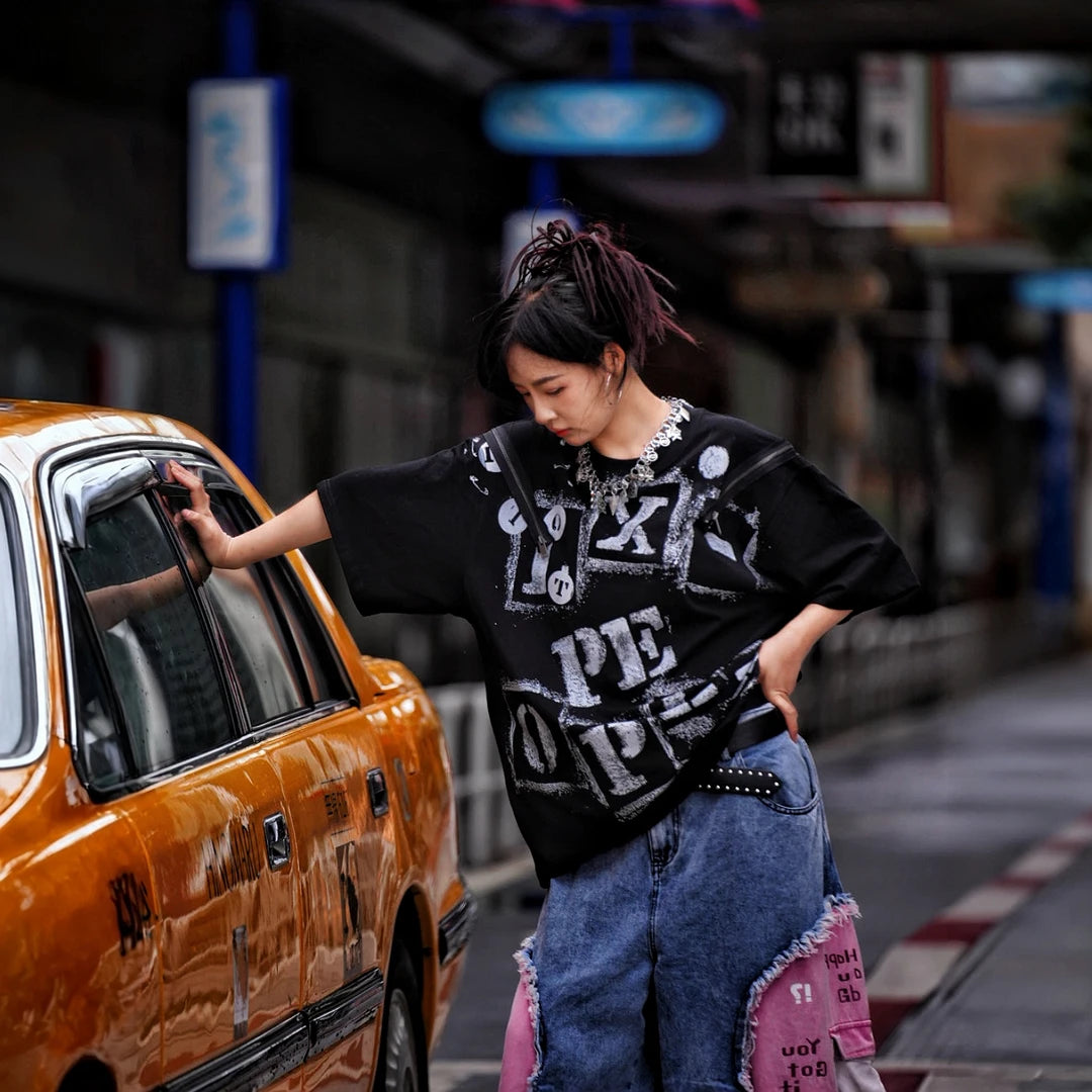 Sanhoostudio short sleeve T-shirt featuring fracture-inspired spray-print artwork, breathable fabric construction, and a relaxed oversized fit. Built for summer streetwear outfits with lightweight comfort and standout graphic styling.