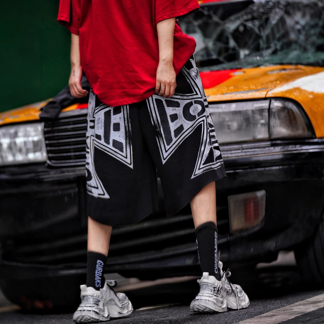 Sanhoostudio shorts featuring distressed wash treatment, graffiti detailing, and cross-inspired design elements with a relaxed fit. Built for summer streetwear outfits with breathable comfort and versatile styling appeal.