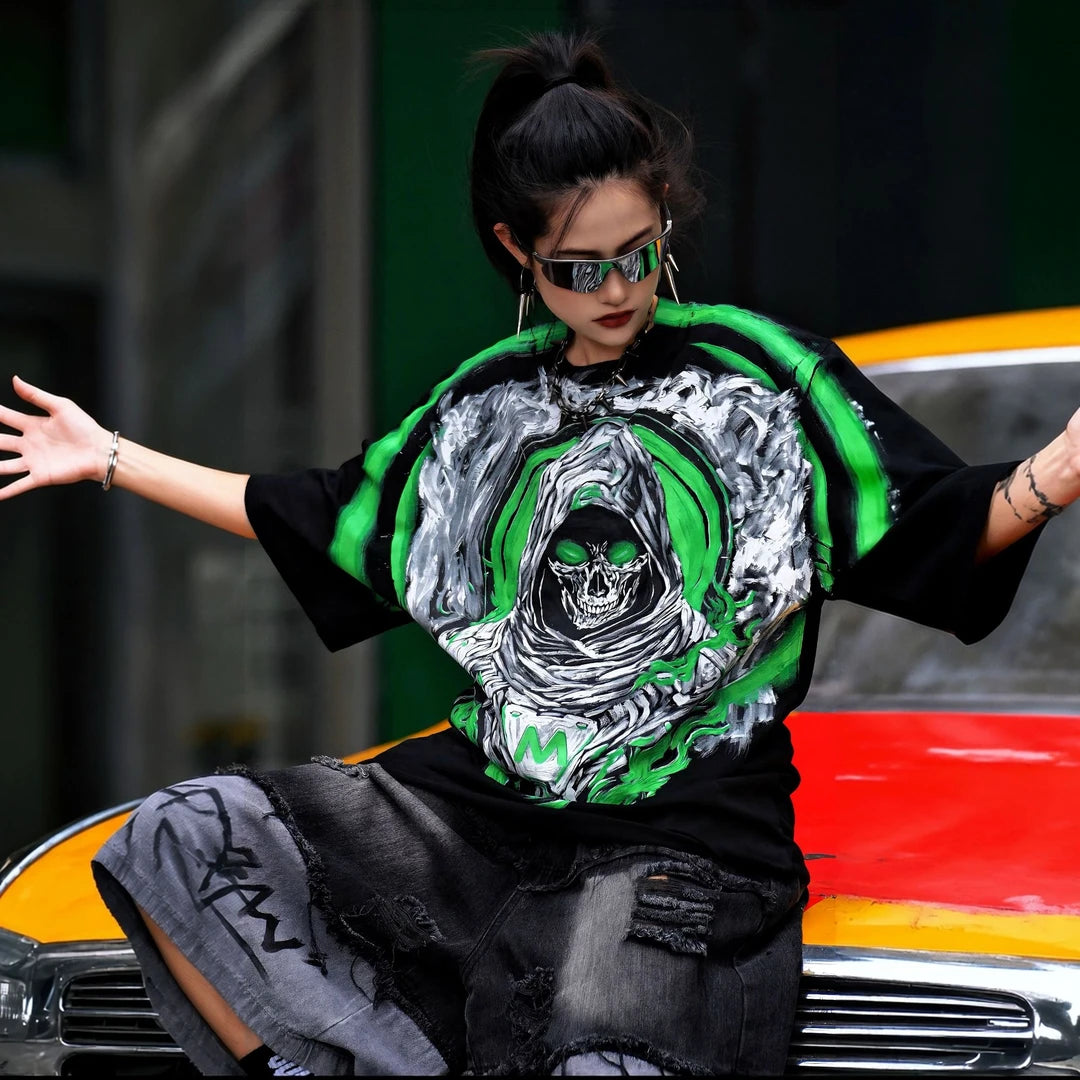 Sanhoostudio short sleeve T-shirt featuring Grim Reaper-inspired artwork, green flame graphics, premium spray-print detailing, and a relaxed oversized silhouette. Built for standout streetwear outfits with breathable comfort and striking visual impact.