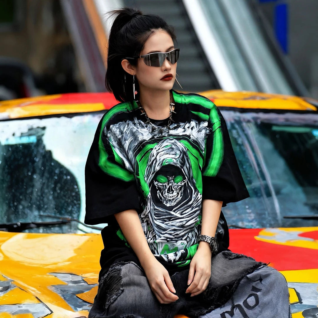 Sanhoostudio short sleeve T-shirt featuring Grim Reaper-inspired artwork, green flame graphics, premium spray-print detailing, and a relaxed oversized silhouette. Built for standout streetwear outfits with breathable comfort and striking visual impact.