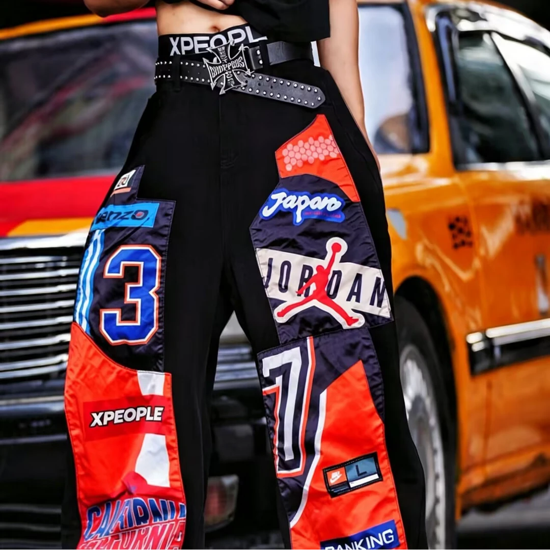 Sanhoostudio denim pants featuring patchwork applique detailing, distressed washed finish, and a wide leg scythe-cut silhouette. Designed for contemporary streetwear styling with relaxed comfort, durable construction, and standout everyday versatility.