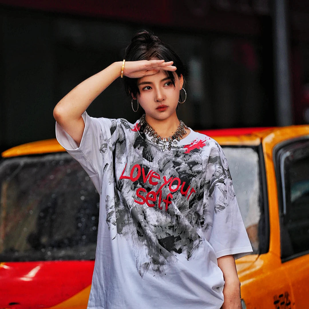 Sanhoostudio short sleeve T-shirt featuring abstract spray-print artwork, breathable fabric construction, and a relaxed oversized fit. Designed for modern streetwear styling with lightweight comfort, bold graphic appeal, and versatile summer wear.