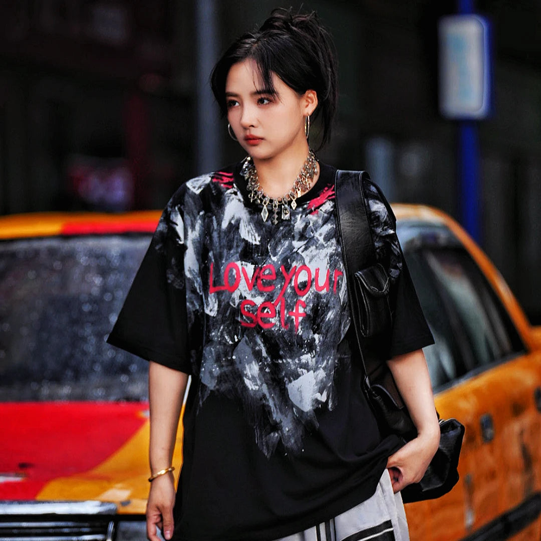 Sanhoostudio short sleeve T-shirt featuring abstract spray-print artwork, breathable fabric construction, and a relaxed oversized fit. Designed for modern streetwear styling with lightweight comfort, bold graphic appeal, and versatile summer wear.