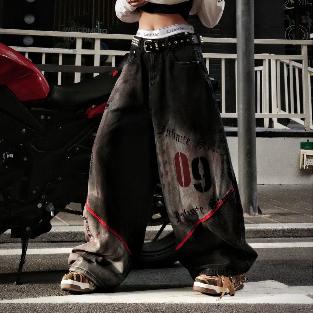 Sanhoostudio denim pants featuring frayed patchwork detailing, distressed wash treatment, and a relaxed scythe-cut silhouette. Designed for modern streetwear styling with a loose straight-leg fit, vintage character, and versatile everyday appeal.