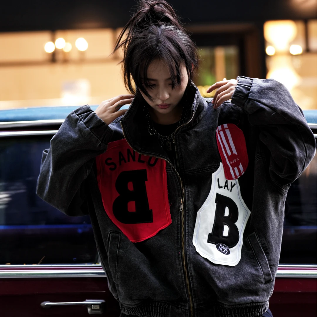 Sanhoostudio denim jacket featuring mixed patch applique embroidery, distressed stain effects, and a relaxed oversized silhouette. Designed for contemporary streetwear layering with handcrafted detailing, rugged denim texture, distinctive visual contrast, and bold everyday styling.