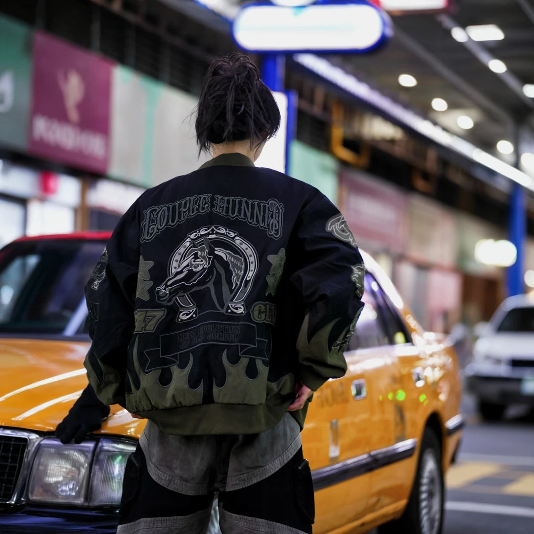 Sanhoostudio padded jacket featuring warhorse-inspired embroidery, contrast patchwork detailing, and a relaxed oversized silhouette. Designed for colder-season streetwear layering with vintage character, comfortable warmth, bold embroidered artwork, and distinctive everyday urban styling.