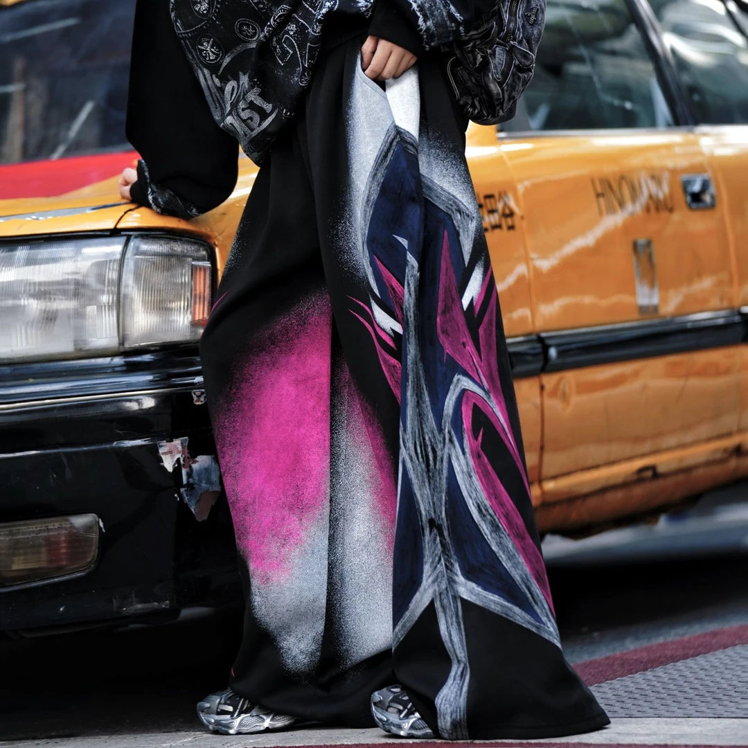 Sanhoostudio sweatpants featuring colorful washed treatment, distressed detailing, patchwork construction, and a relaxed wide leg scythe silhouette. Designed for statement streetwear styling with heavyweight texture, comfortable movement, oversized proportions, and distinctive everyday appeal.