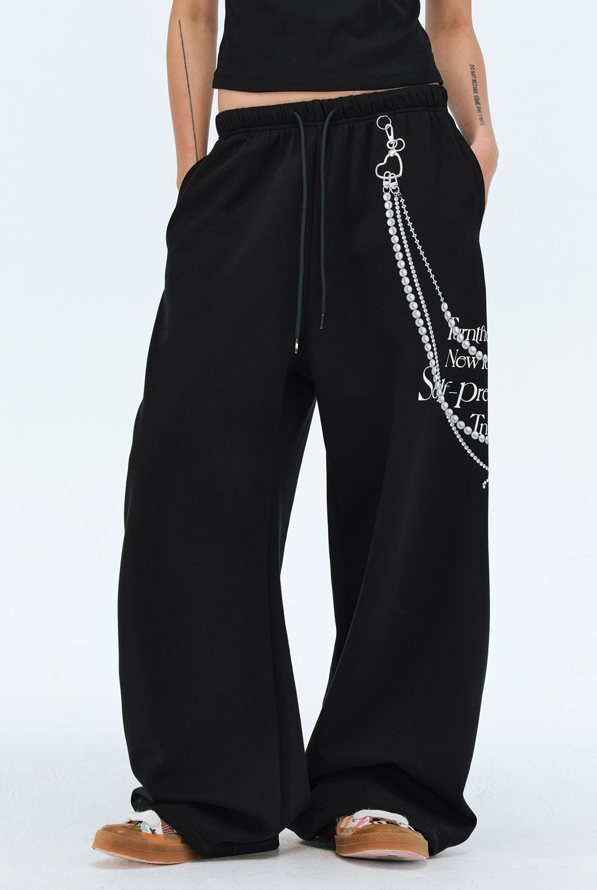 These Sanhoostudio pants stand out with pearl chain embellishments and bold slogan prints, merging casual comfort with high street individuality. Designed with a relaxed fit, they highlight a balance of playful accessories and edgy fashion vibes.
