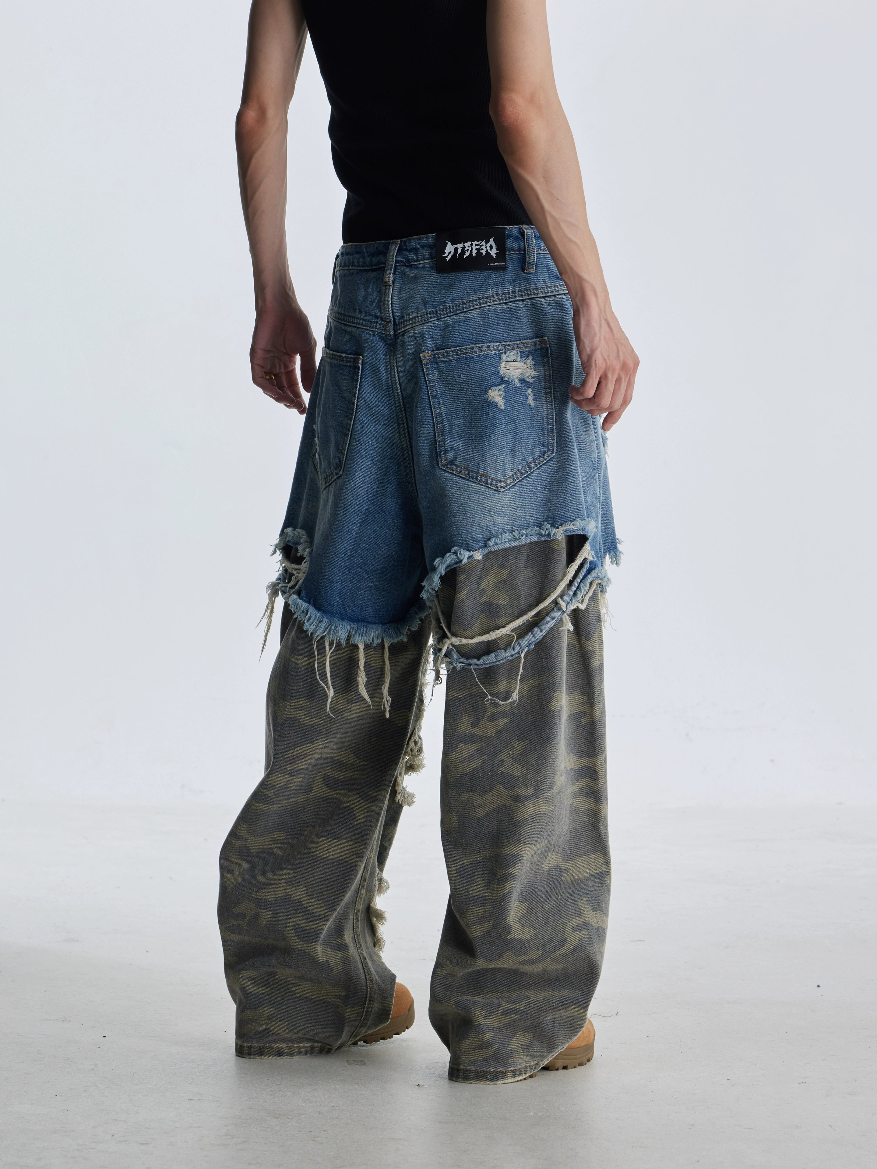 These deconstructed patchwork camo jeans from Sanhoostudio feature a unique layered fake two-piece effect, distressed ripped accents, and a loose straight-leg silhouette. Combining vintage inspiration with edgy high street aesthetics, they are perfect for streetwear lovers seeking comfort, individuality.