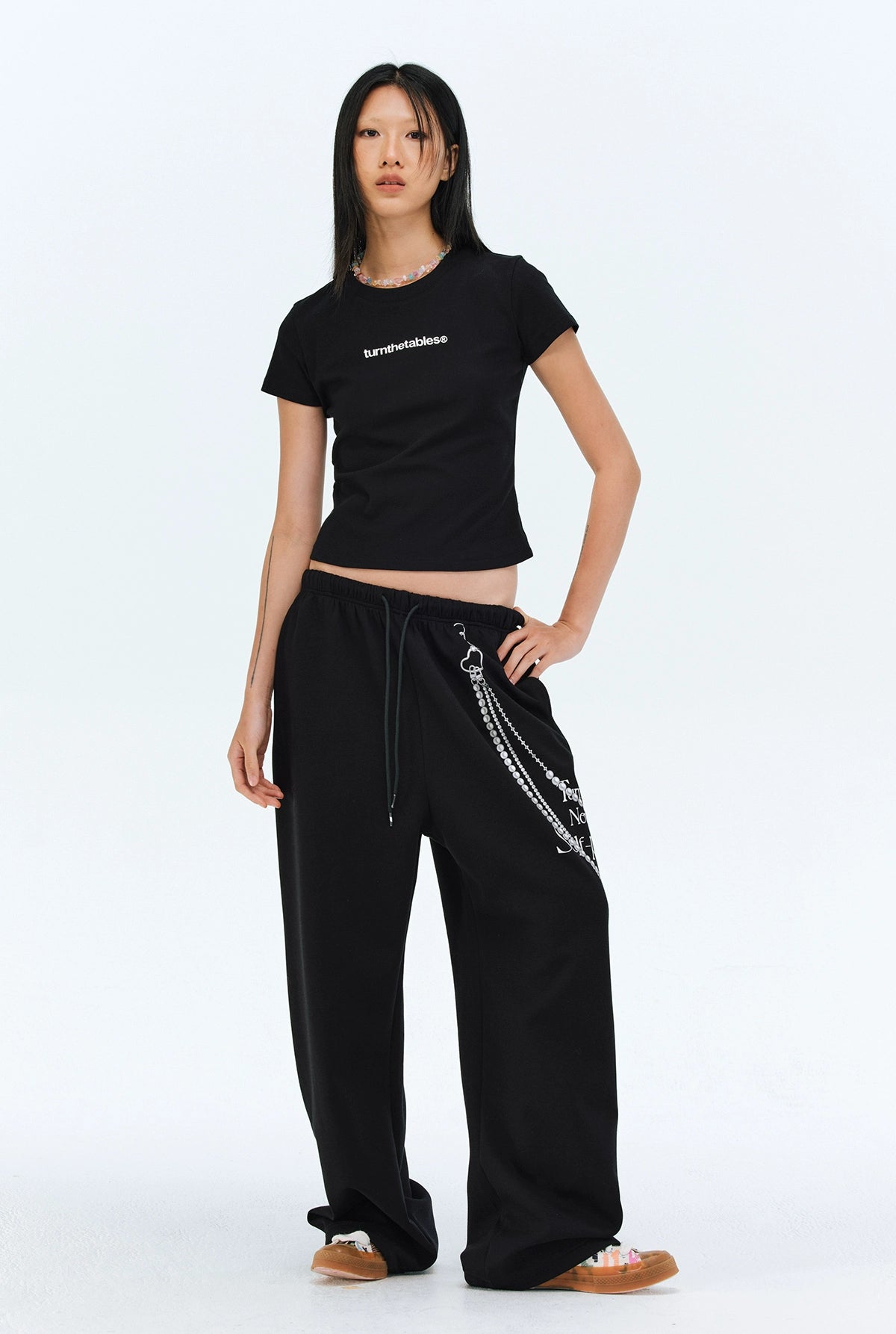 These Sanhoostudio pants stand out with pearl chain embellishments and bold slogan prints, merging casual comfort with high street individuality. Designed with a relaxed fit, they highlight a balance of playful accessories and edgy fashion vibes.