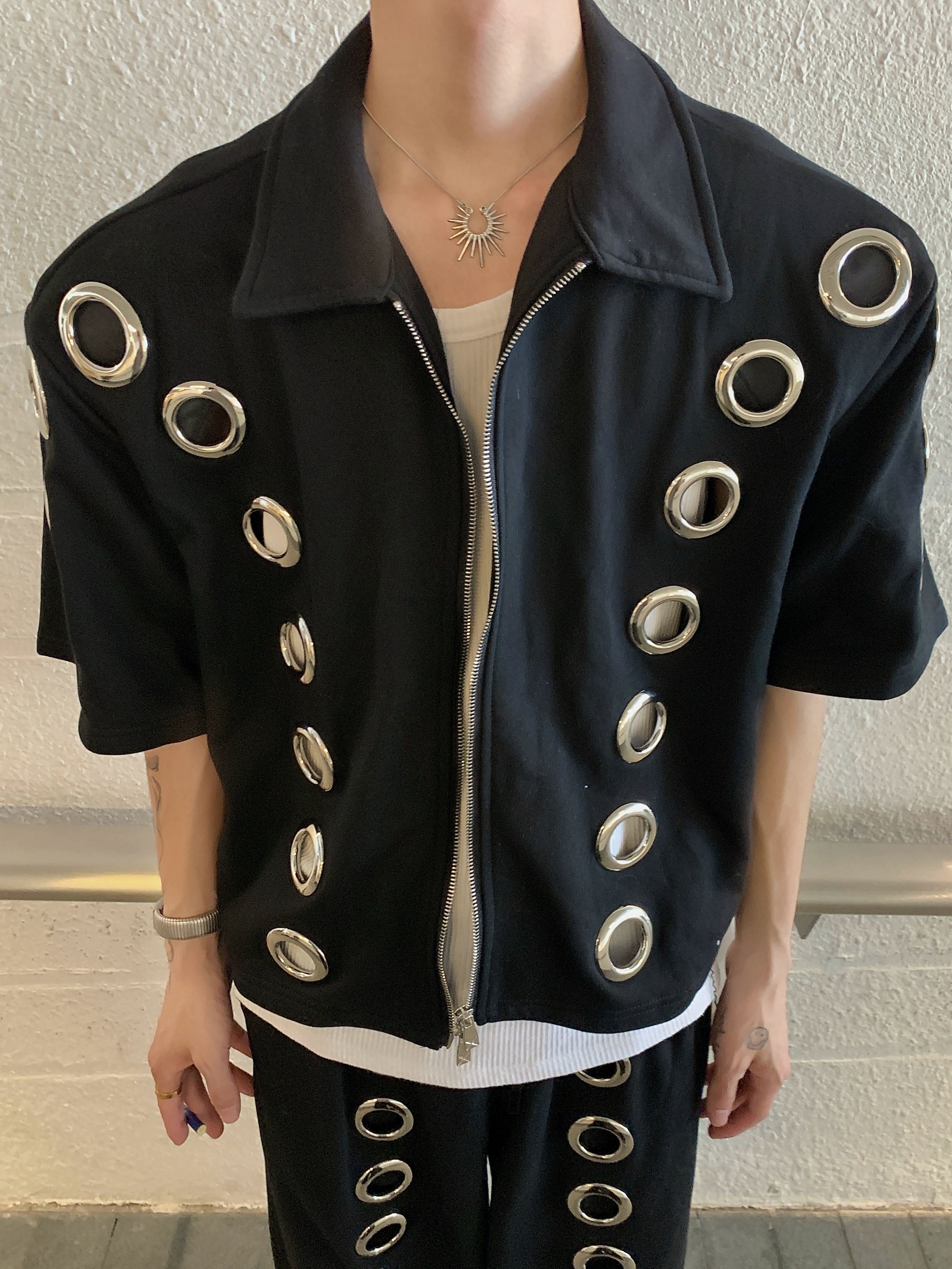 The Sanhoostudio two-piece set combines a cropped hoodie with metal ring hollow details and a matching bottom for a coordinated high street look. With its relaxed fit and edgy design, this set delivers both comfort and standout individuality for streetwear enthusiasts.