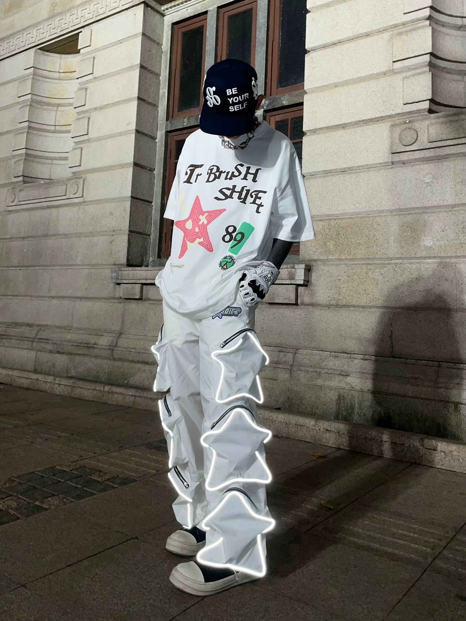 These reflective cargo pants from Sanhoostudio feature 3D star patches and bold avant-garde styling. The oversized fit and dark aesthetic make them ideal for nightwear, performance looks, or urban outfits, blending futuristic energy with functional streetwear practicality.