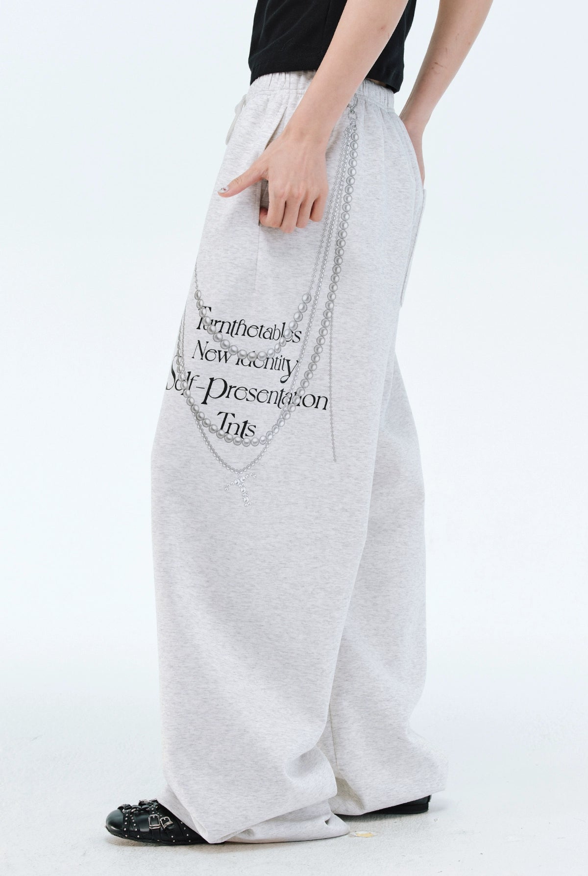 These Sanhoostudio pants stand out with pearl chain embellishments and bold slogan prints, merging casual comfort with high street individuality. Designed with a relaxed fit, they highlight a balance of playful accessories and edgy fashion vibes.