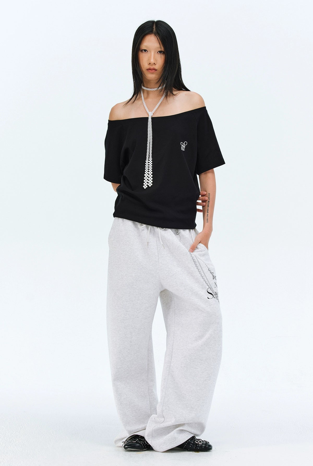 These Sanhoostudio pants stand out with pearl chain embellishments and bold slogan prints, merging casual comfort with high street individuality. Designed with a relaxed fit, they highlight a balance of playful accessories and edgy fashion vibes.