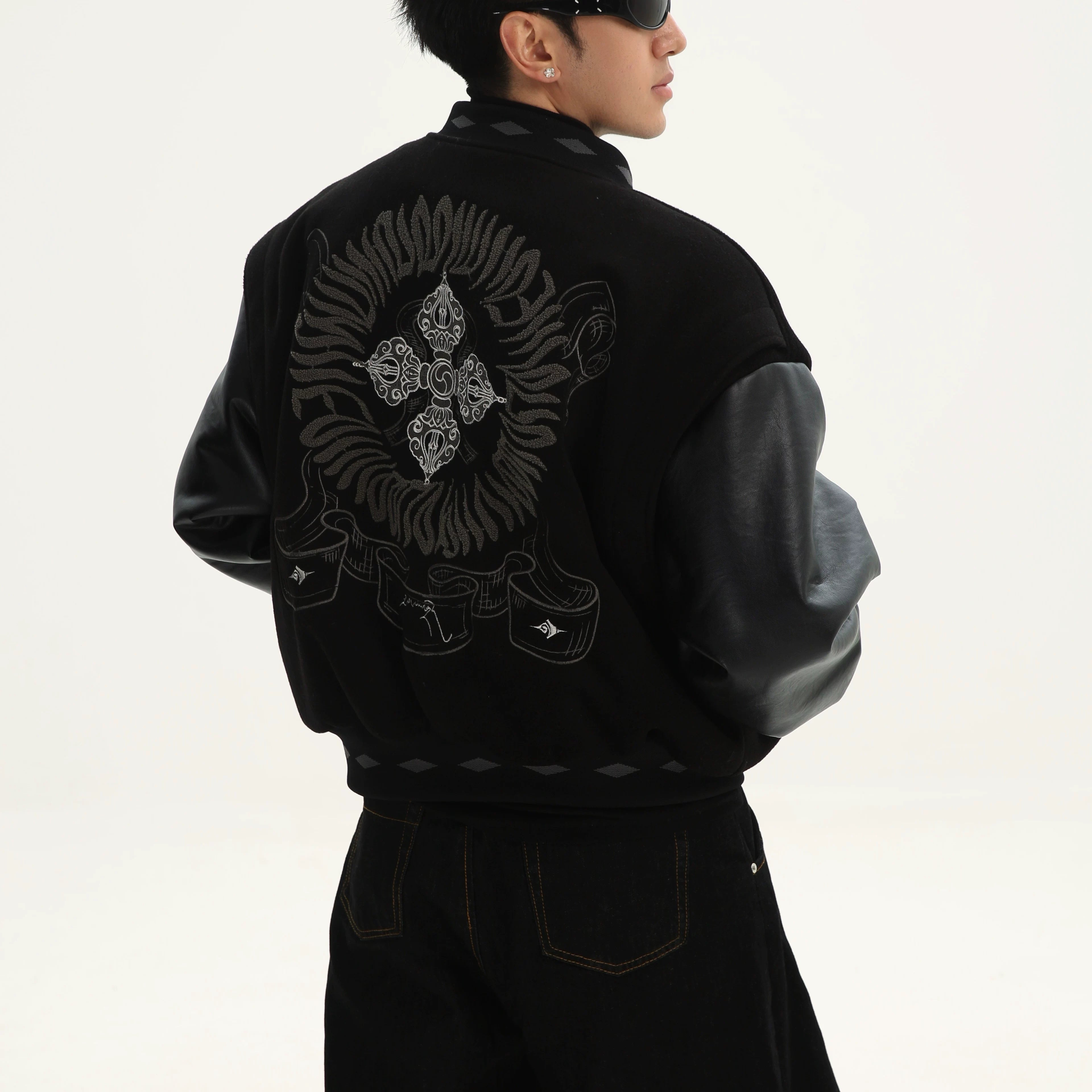 Sanhoostudio varsity jacket from the Dojie Unbound series, featuring Tibetan-inspired embroidery and heavyweight construction.
