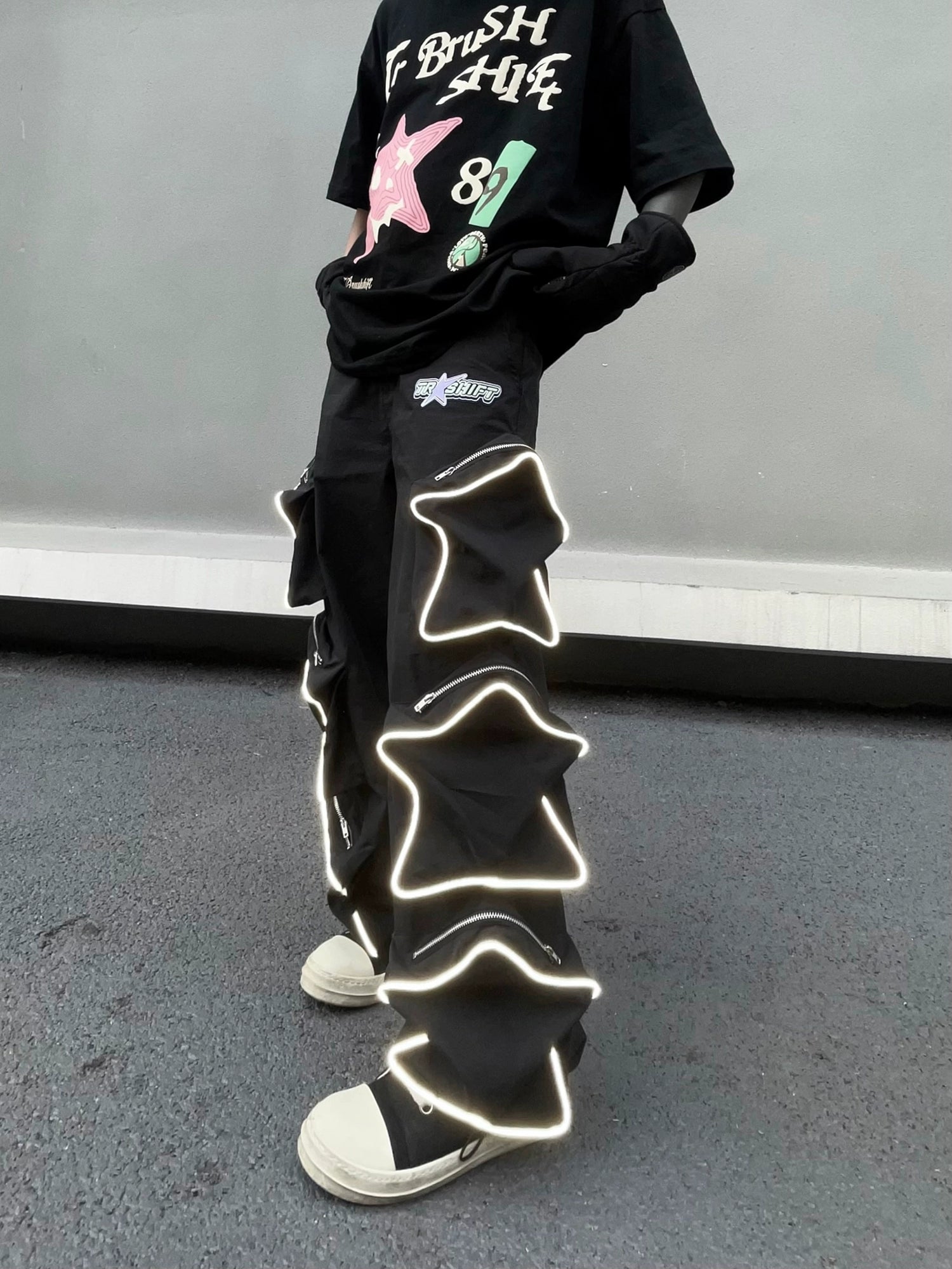 These reflective cargo pants from Sanhoostudio feature 3D star patches and bold avant-garde styling. The oversized fit and dark aesthetic make them ideal for nightwear, performance looks, or urban outfits, blending futuristic energy with functional streetwear practicality.