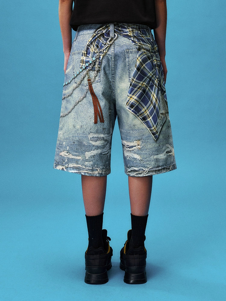 These Sanhoostudio denim shorts feature plaid-inspired patterns with chain print accents, merging casual denim with bold graphic expression. With a relaxed oversized fit, they’re ideal for layering into creative high street looks.