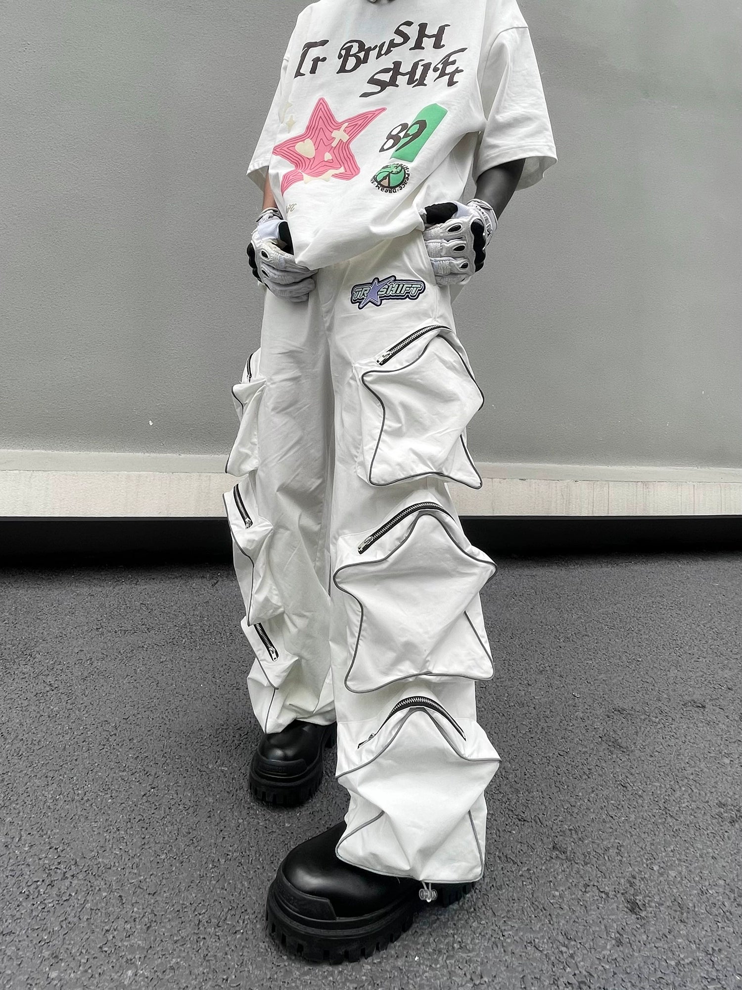 These reflective cargo pants from Sanhoostudio feature 3D star patches and bold avant-garde styling. The oversized fit and dark aesthetic make them ideal for nightwear, performance looks, or urban outfits, blending futuristic energy with functional streetwear practicality.