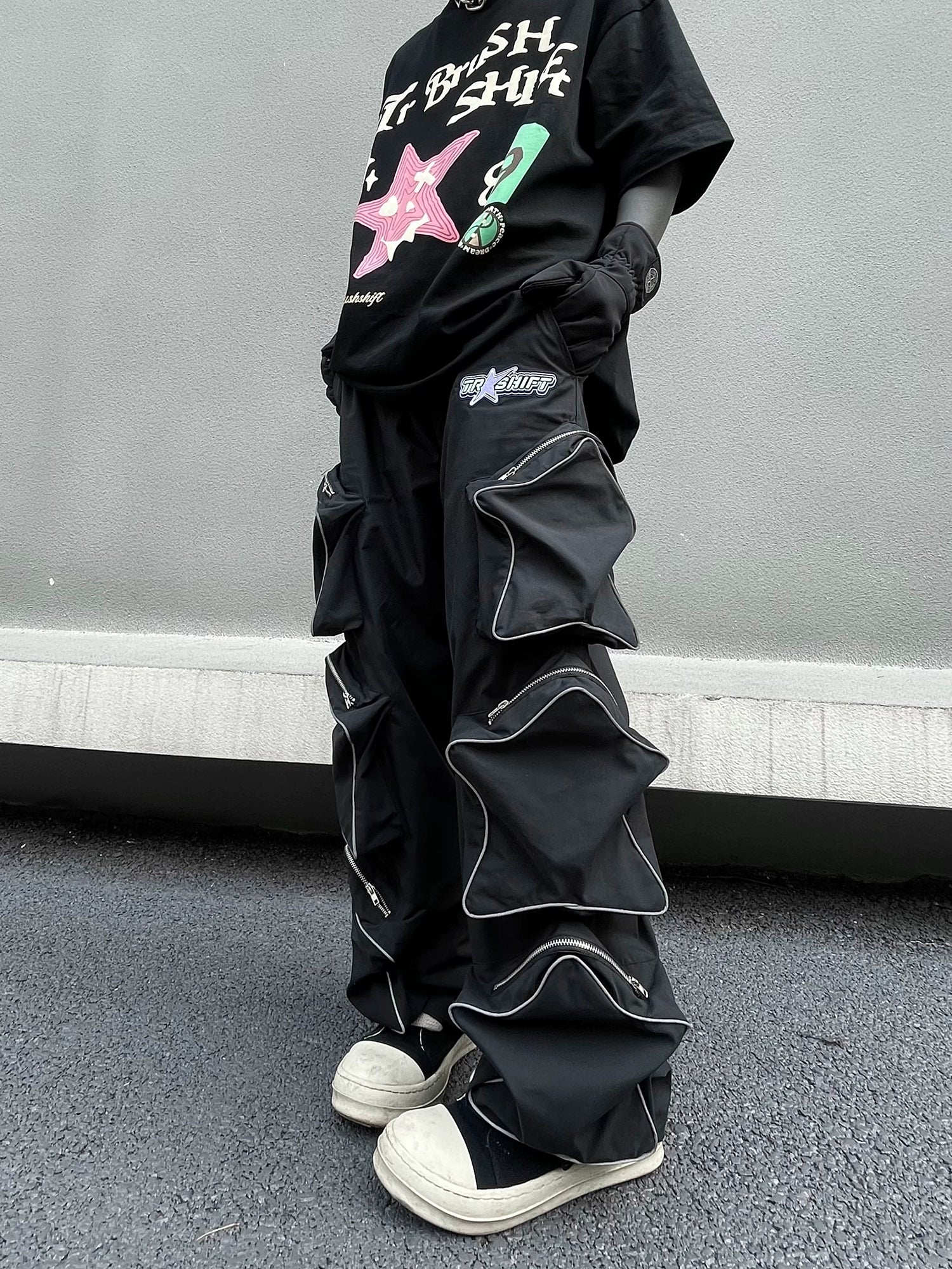 These reflective cargo pants from Sanhoostudio feature 3D star patches and bold avant-garde styling. The oversized fit and dark aesthetic make them ideal for nightwear, performance looks, or urban outfits, blending futuristic energy with functional streetwear practicality.