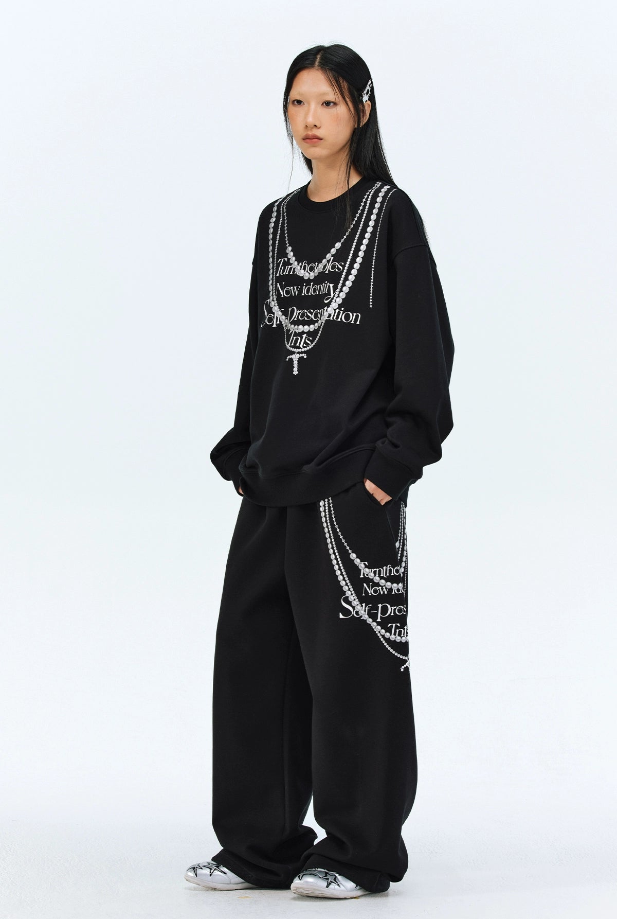These Sanhoostudio pants stand out with pearl chain embellishments and bold slogan prints, merging casual comfort with high street individuality. Designed with a relaxed fit, they highlight a balance of playful accessories and edgy fashion vibes.