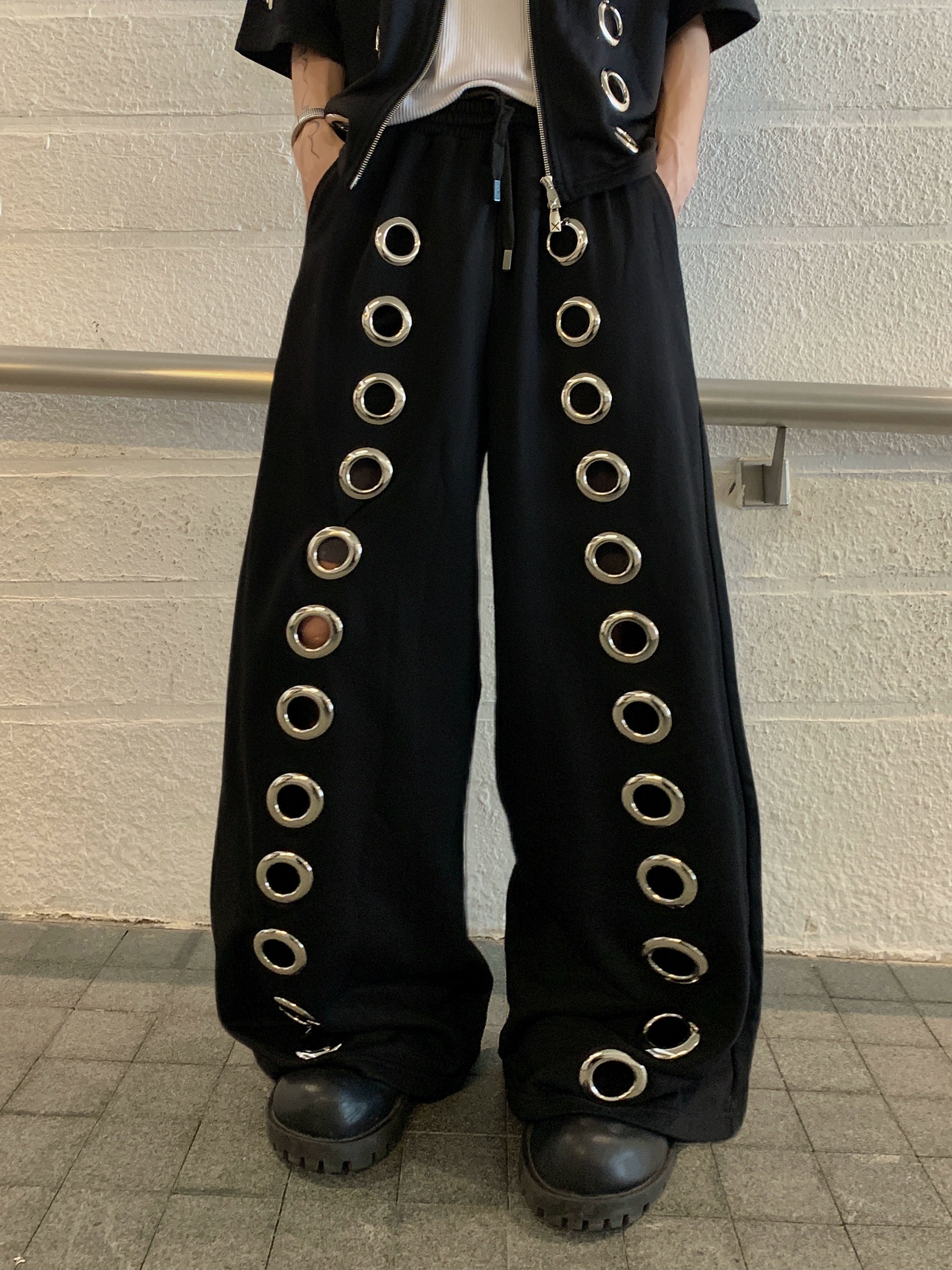 The Sanhoostudio two-piece set combines a cropped hoodie with metal ring hollow details and a matching bottom for a coordinated high street look. With its relaxed fit and edgy design, this set delivers both comfort and standout individuality for streetwear enthusiasts.