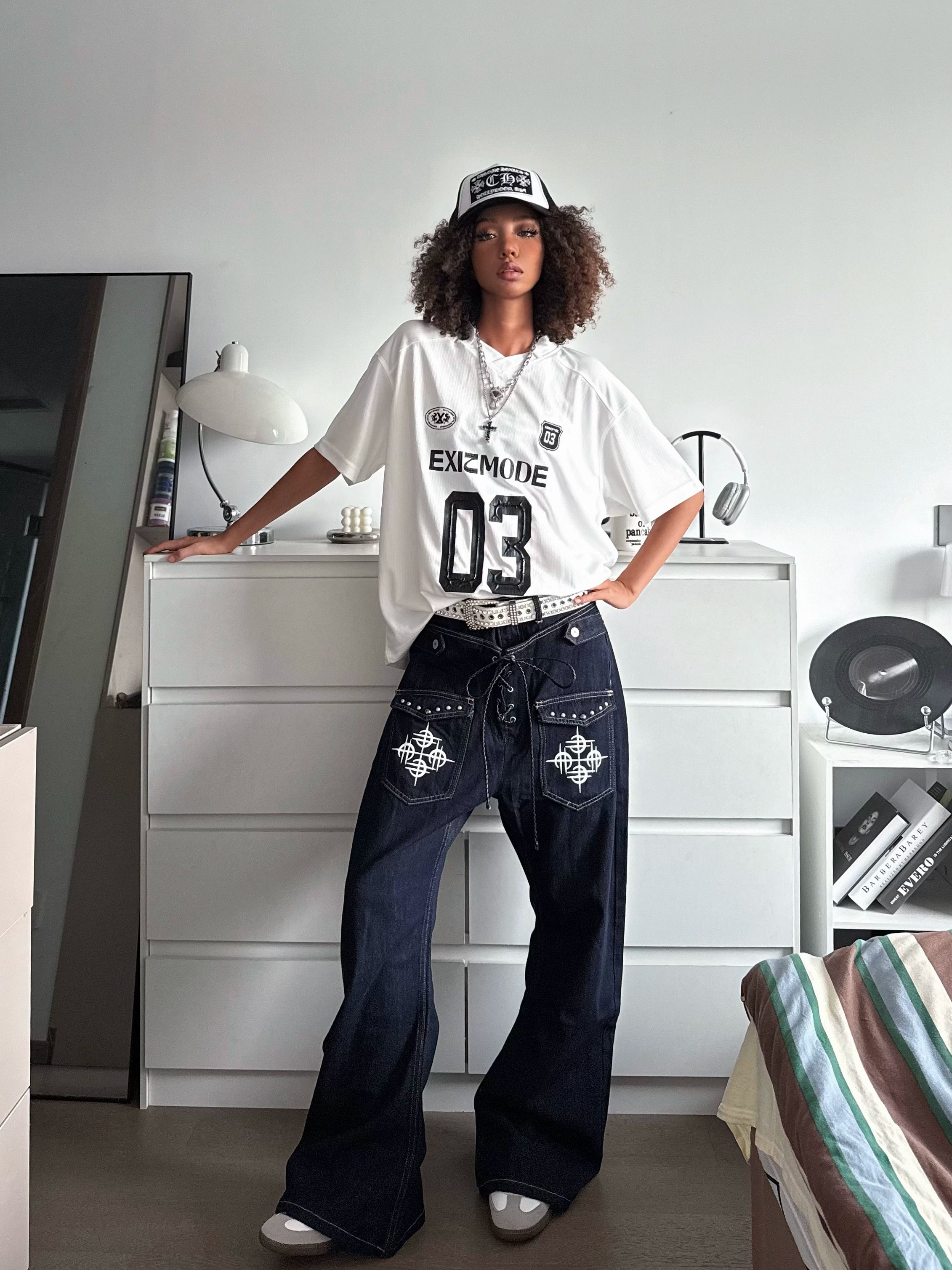 The Sanhoostudio double-waist jeans showcase a unique studded drawstring design with blade-cut legs. Their deconstructed silhouette and washed finish bring punk-inspired energy to everyday streetwear styling, making them a bold wardrobe choice.