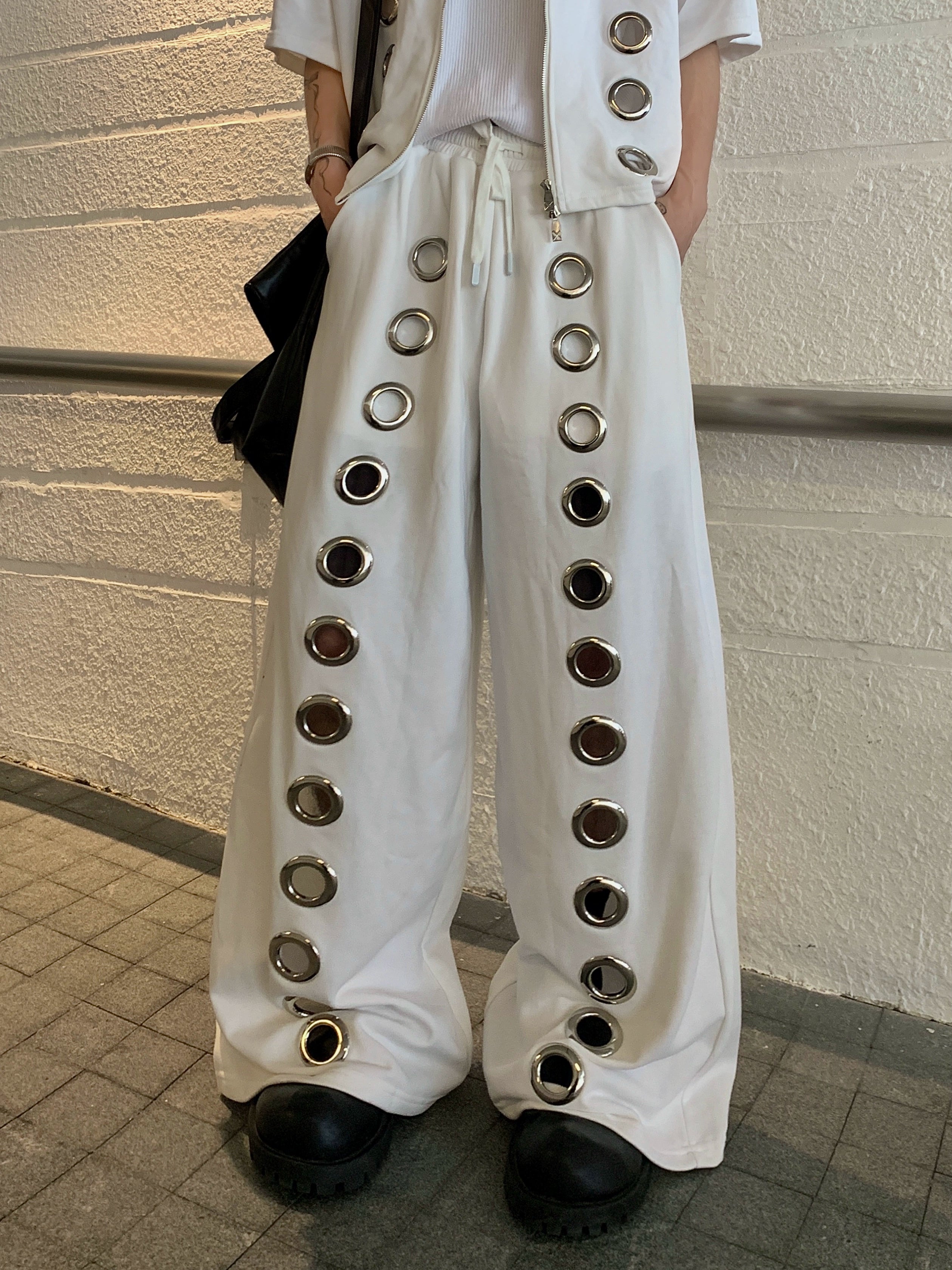 The Sanhoostudio two-piece set combines a cropped hoodie with metal ring hollow details and a matching bottom for a coordinated high street look. With its relaxed fit and edgy design, this set delivers both comfort and standout individuality for streetwear enthusiasts.