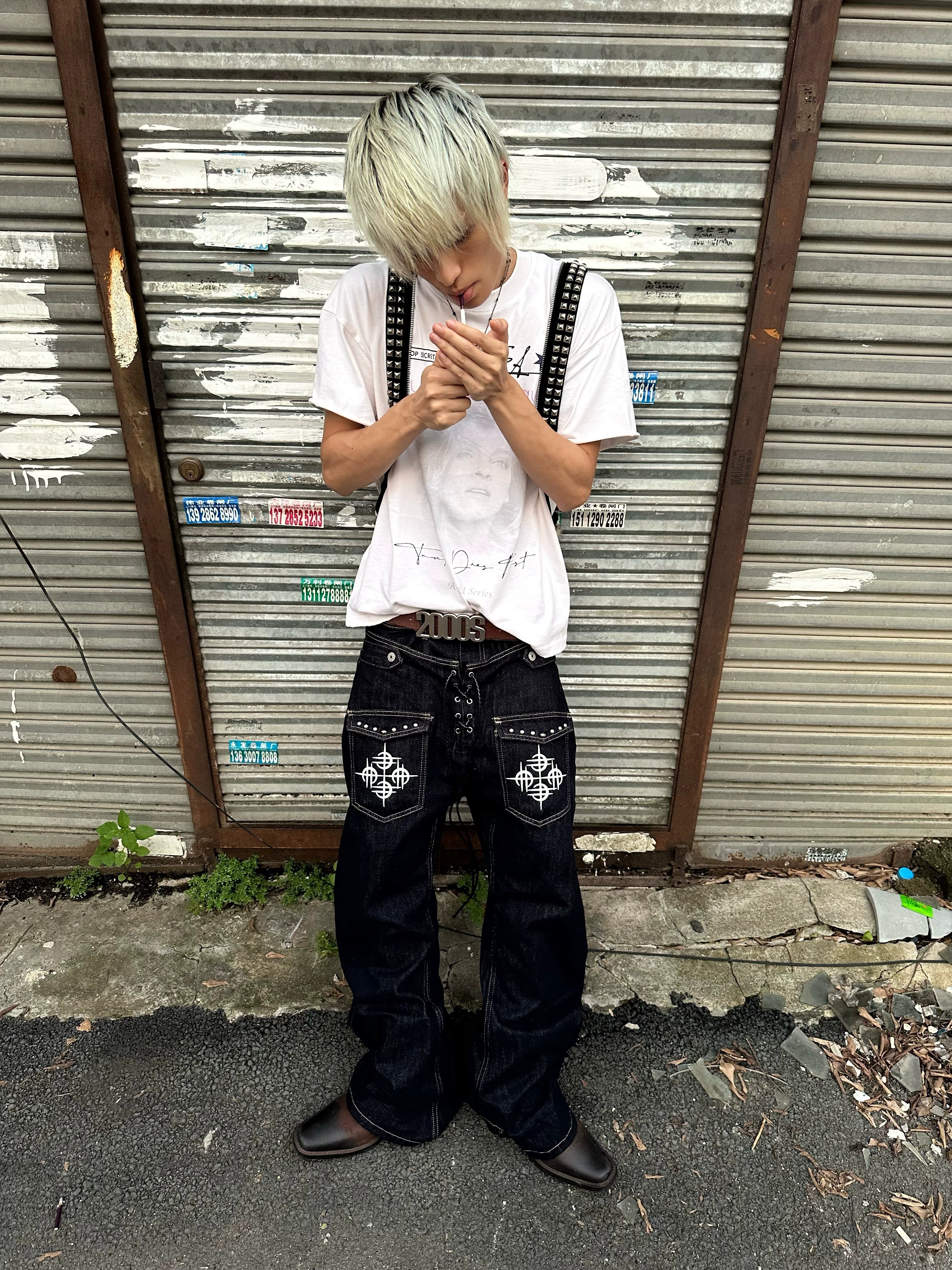 The Sanhoostudio double-waist jeans showcase a unique studded drawstring design with blade-cut legs. Their deconstructed silhouette and washed finish bring punk-inspired energy to everyday streetwear styling, making them a bold wardrobe choice.