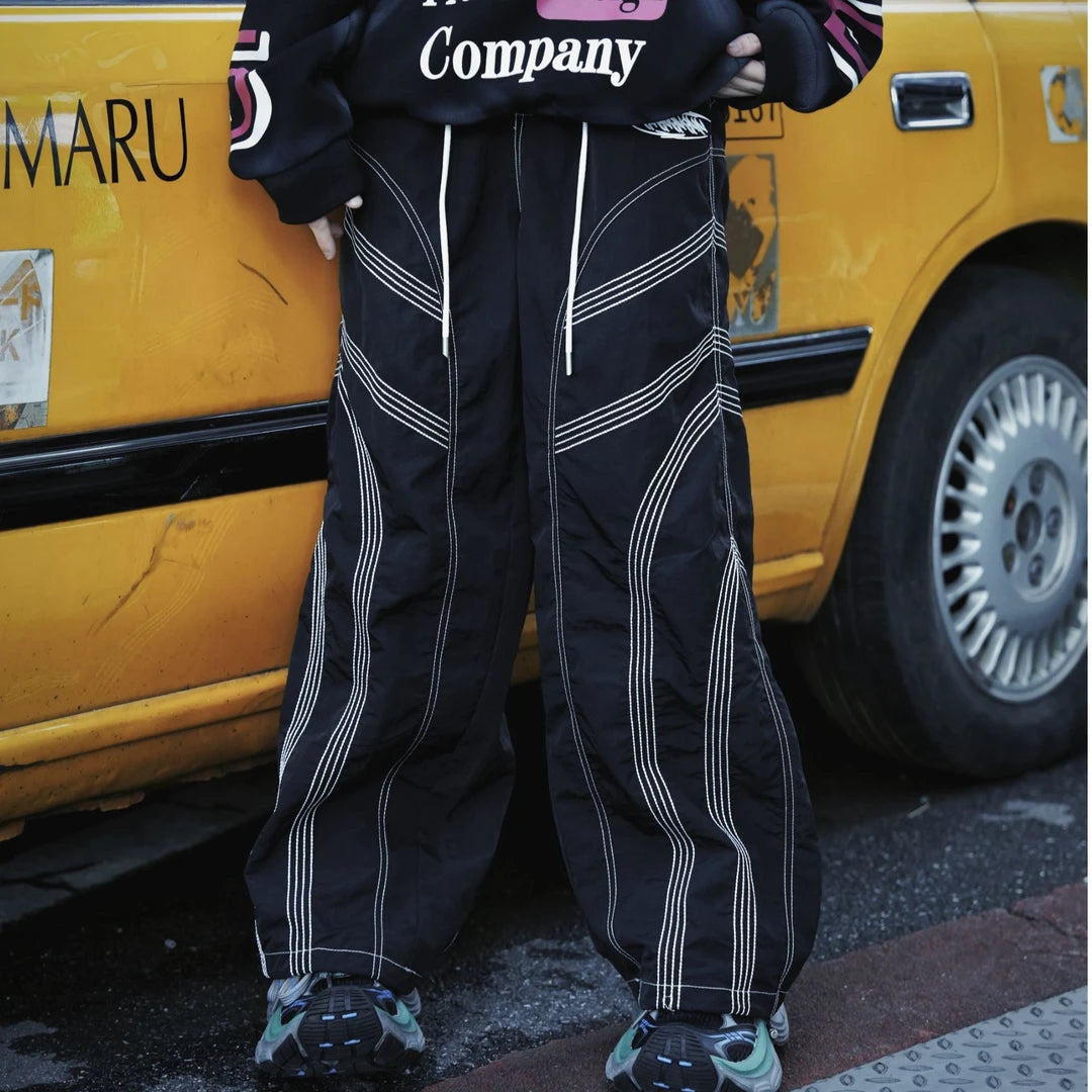 Straight-leg hip-hop pants featuring embroidered contrast stitching, deconstructed patchwork, and a dry-fit breathable build.