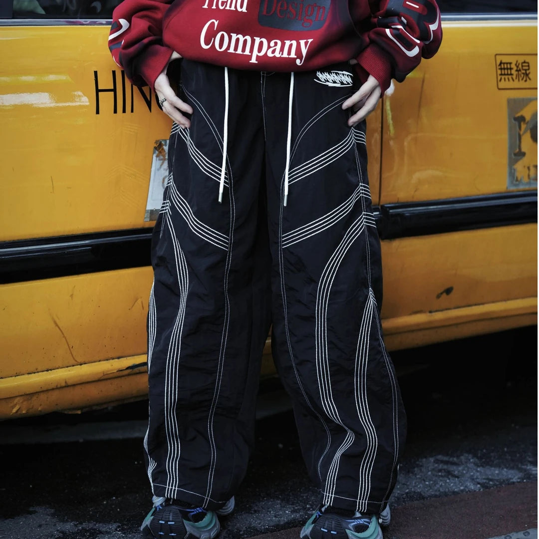 Straight-leg hip-hop pants featuring embroidered contrast stitching, deconstructed patchwork, and a dry-fit breathable build.