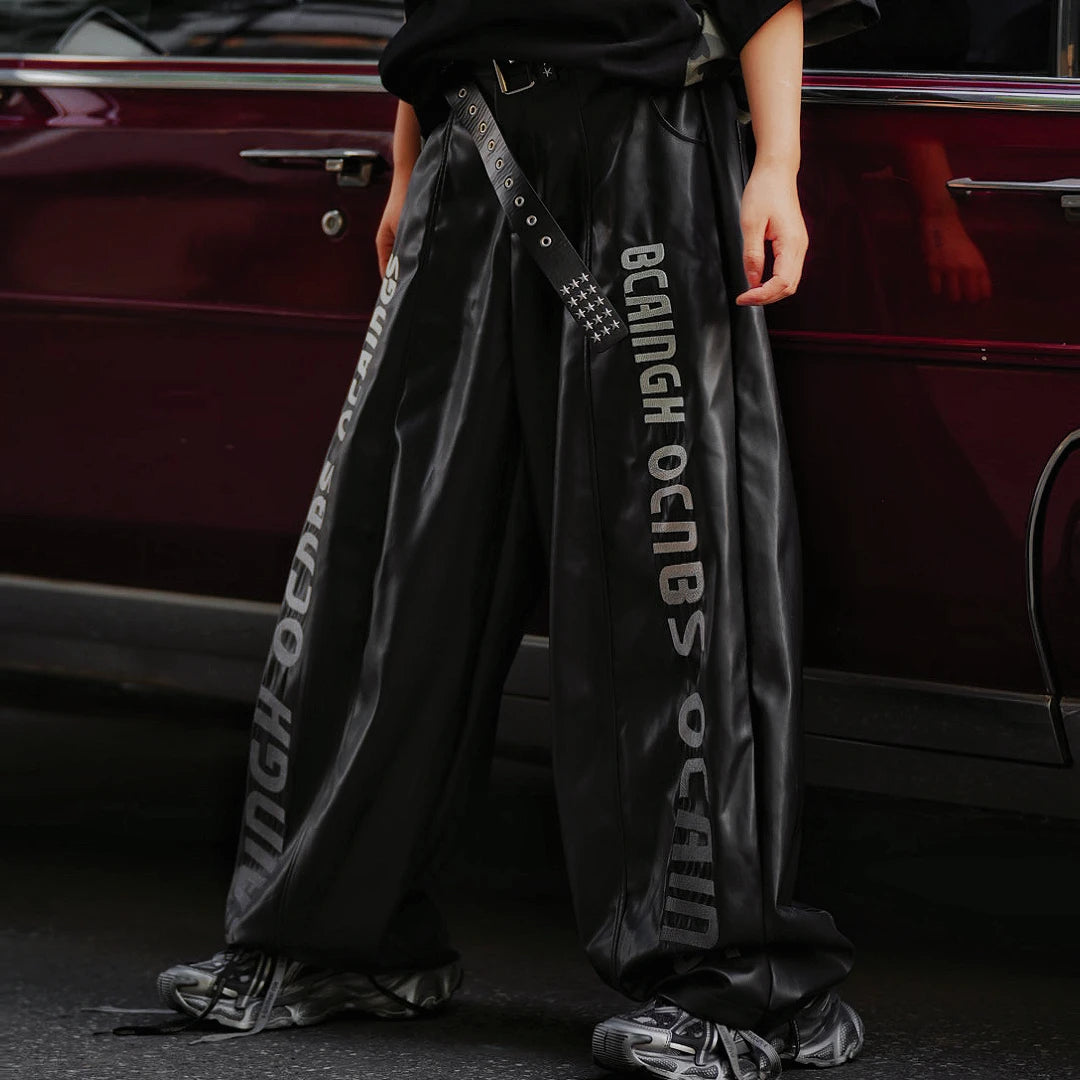 Sanhoostudio washed leather pants featuring gradient letter embroidery, distressed finish, and graffiti patchwork detailing. Heavyweight unisex streetwear pants designed for bold winter styling.