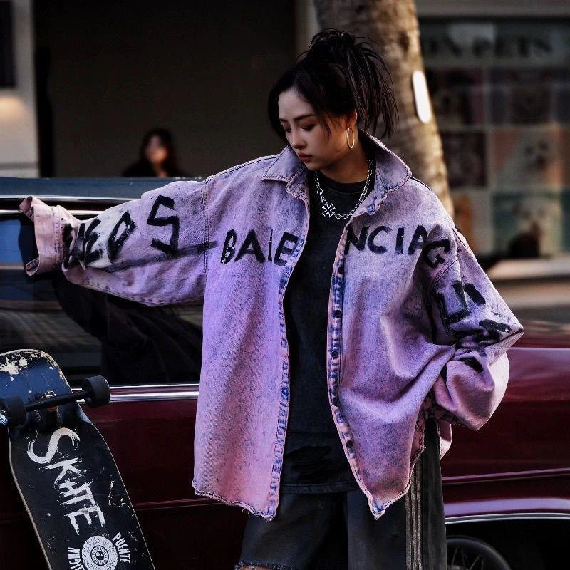 Sanhoostudio denim shirt jacket featuring Paris-inspired graffiti artwork and distressed washed finish in dusty pink tone. Designed with a loose fit and classic collar for modern vintage streetwear styling.